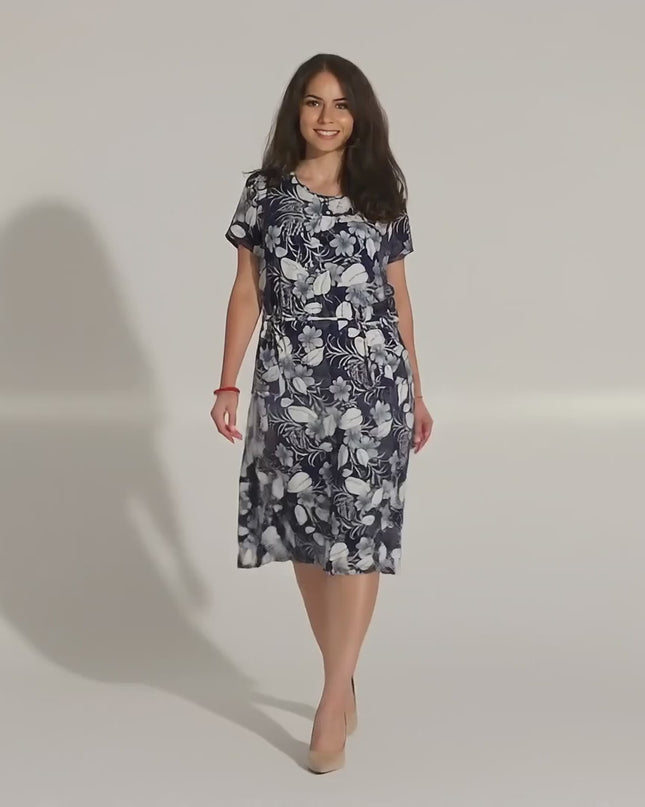 Видео представяне в студийна среда с неутрален фон, където макси модел върви бавно към камерата, облечена в Елегантна лятна рокля с джобове и флорален десен