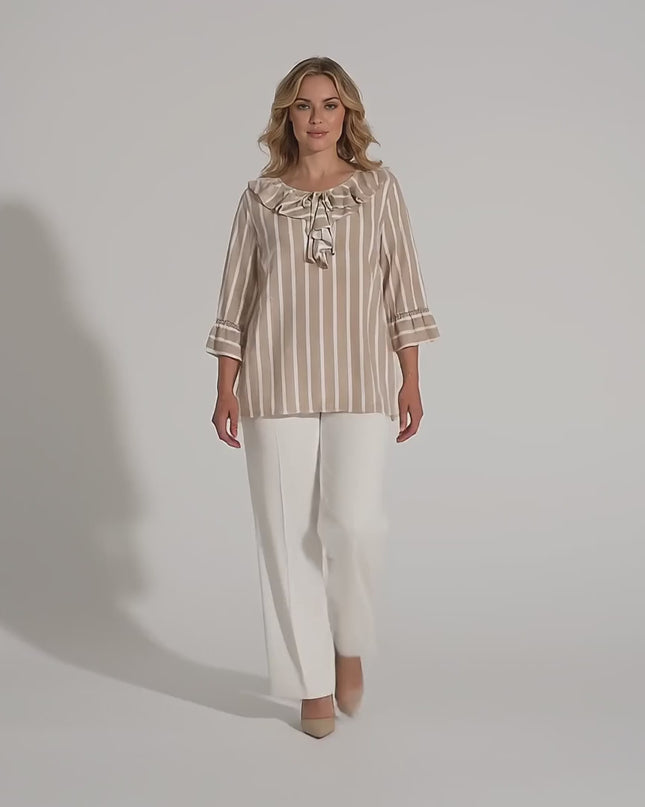 Макси модел в студийна среда на неутрален фон върви бавно към камерата, облечена с Официална разкроена туника на райе в бежово и бяло