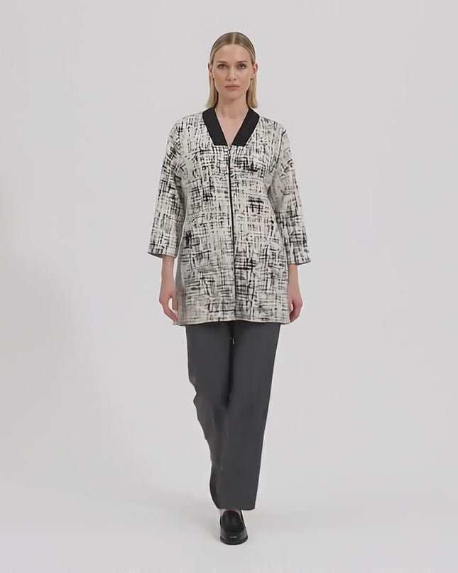 Студийно видео, в което модел носи Дамски бежов макси жакет с цип и абстрактен десен и върви бавно към камерата на неутрален фон