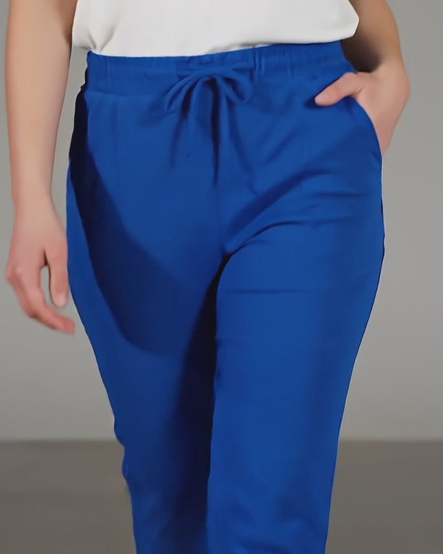 Видео в студийна среда показващо как модел носи Дамски панталон големи размери в кралскосин цвят с ластик и връзки и върви бавно към камерата на неутрален фон