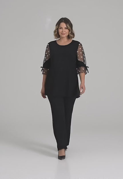 Видео на модел който върви към камерата и представя Официална черна туника големи размери с ефектен тюл на точки и панделка в студийна среда