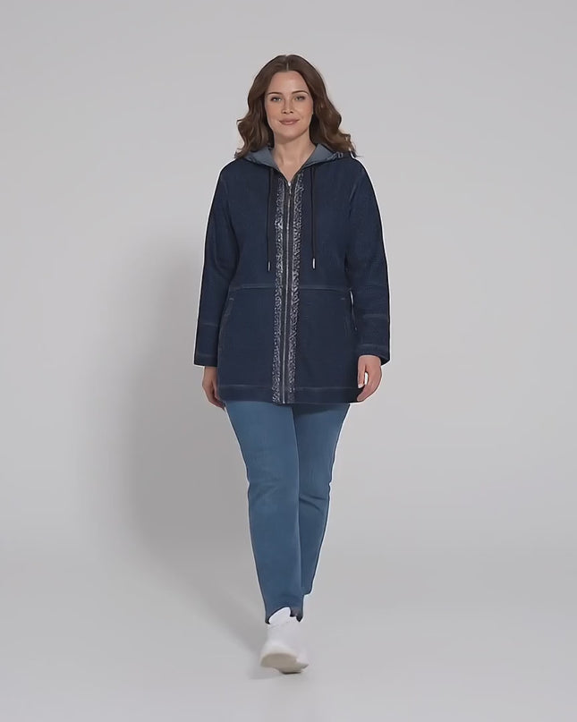 Продуктово видео в студио, в което плюс сайз модел носи Дълго тъмносиньо макси дънково яке с качулка и върви бавно към камерата на неутрален фон