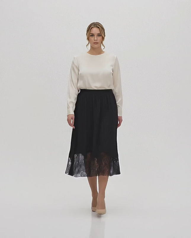 Плюс размер модел, облечен в Официална черна макси пола с дантела, върви бавно към камерата в студио с неутрален фон