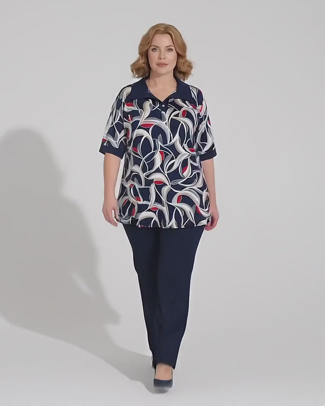 Студийно видео, в което модел носи Елегантна разкроена туника големи размери в шарен десен и върви бавно към камерата на неутрален фон