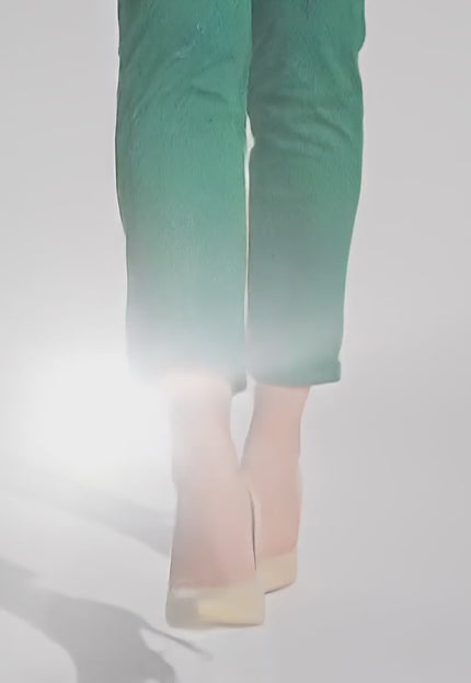 Продуктово видео в студио показващо как макси модел носи Елегантен зелен макси панталон на черни точки и еластична талия и върви бавно към камерата на неутрален фон