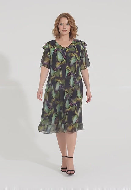 Видео представяне в студийна среда на плюс размер модел, който е облечен с Официална шифонена рокля в пъстър десен с разкроена кройка и върви бавно към камерата