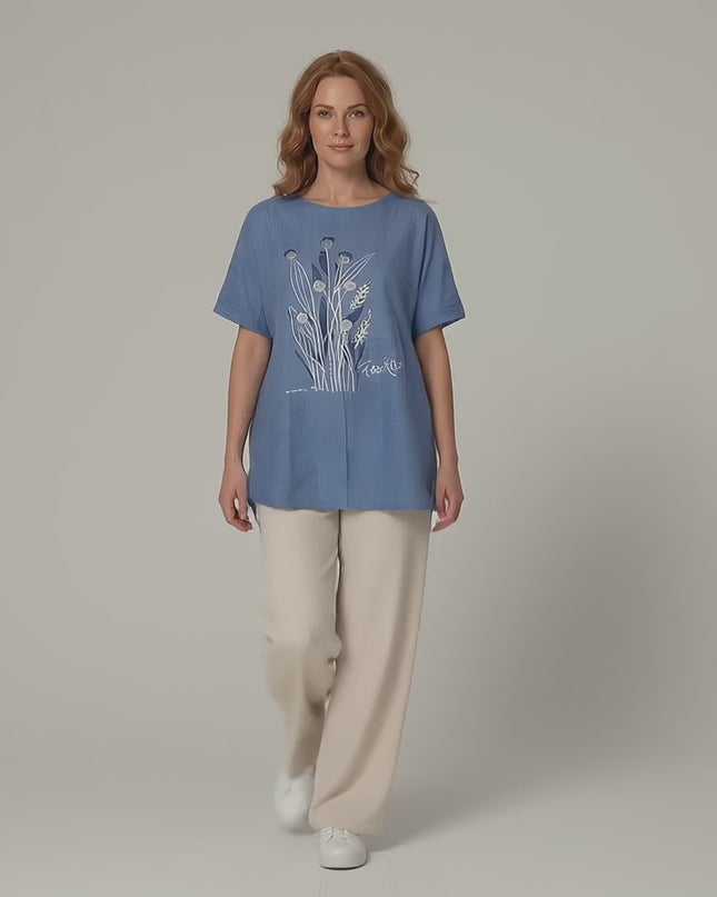 Видео в студийна среда, показващо жена модел на неутрален фон, която върви бавно към камерата, облечена в Синя лятна туника големи размери с дантела и цветя