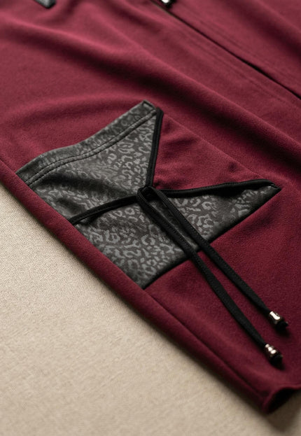 Детайл отблизо на разкроен макси елек в цвят бордо, показващ джоб с елементи от еко кожа и връзки с метални накрайници.