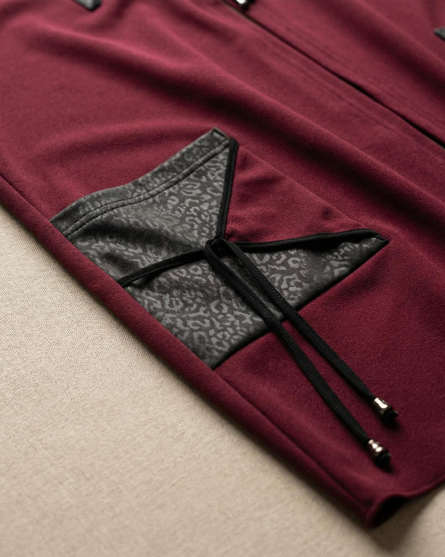 Детайл отблизо на разкроен макси елек в цвят бордо, показващ джоб с елементи от еко кожа и връзки с метални накрайници.