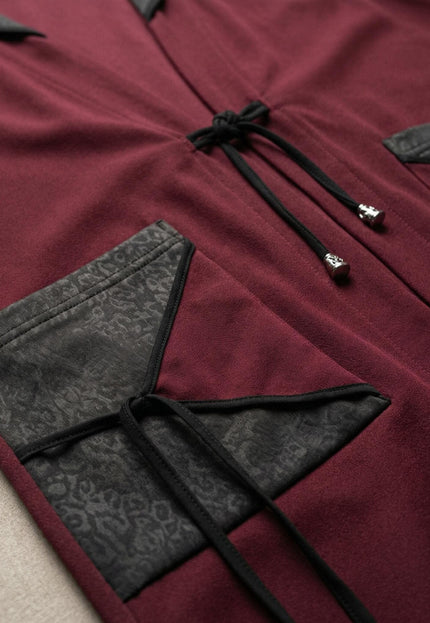 Детайлна снимка на разкроен макси елек в бордо, фокусирана върху джоба с елемент от текстурирана еко кожа и връзките с метални накрайници