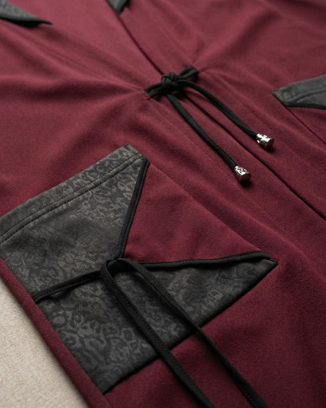 Детайлна снимка на разкроен макси елек в бордо, фокусирана върху джоба с елемент от текстурирана еко кожа и връзките с метални накрайници