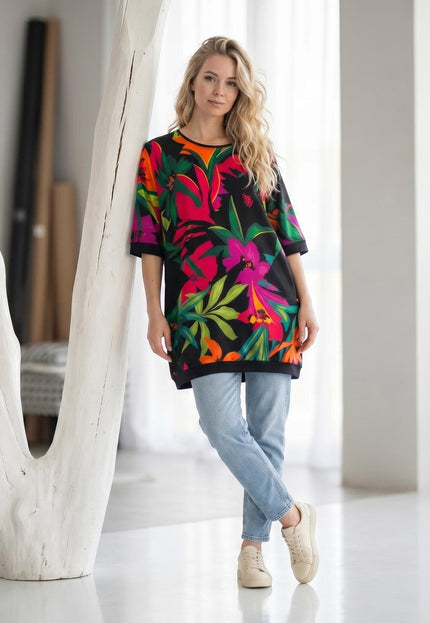 Шарена лятна туника с къс ръкав и тропически флорален принт на черен фон, представена в цял ръст върху модел.