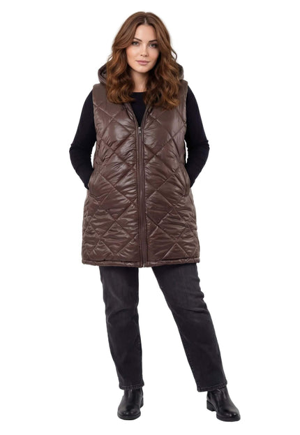 Шоколадово кафяв дълъг ватиран елек с качулка и диамантено капитониране, заснет в цял ръст отпред върху бял фон.