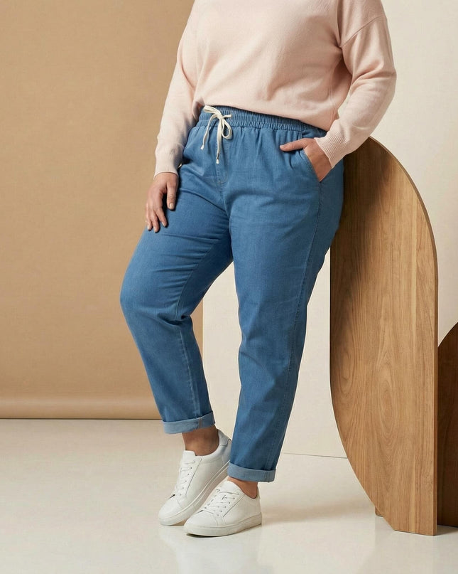 Дамски сини летни дънки големи размери с права кройка, ластик в талията с бели връзки и навити крачоли, 3/4 кадър.