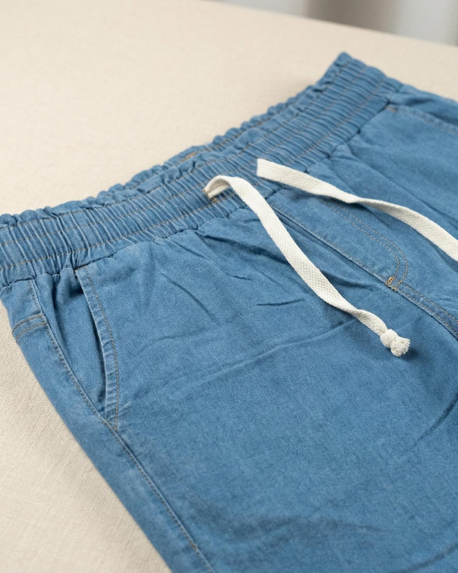 Детайл отблизо на сини летни дънки големи размери. Акцент върху ластичната талия с бели връзки и преден джоб.