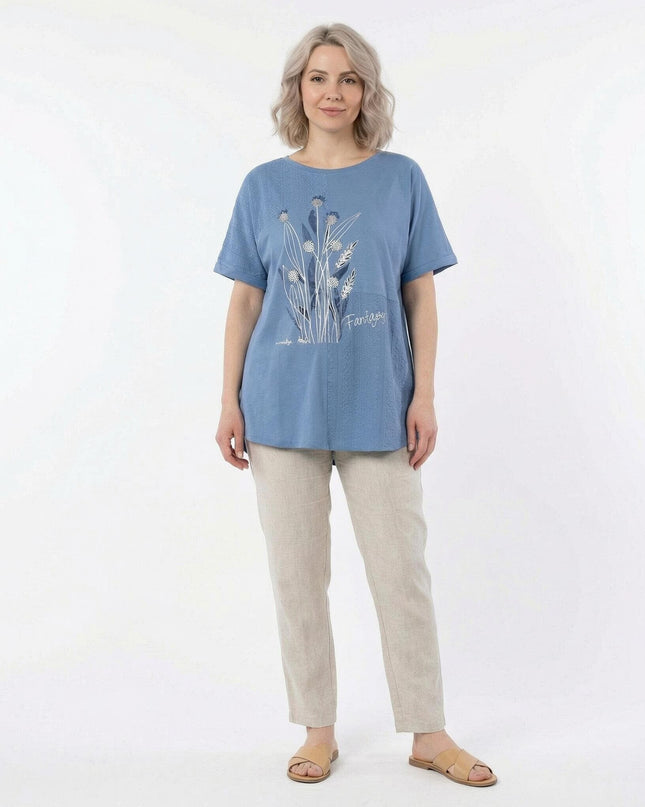 Синя лятна туника големи размери с красива флорална апликация и къси ръкави, представена в цял ръст на бял фон.