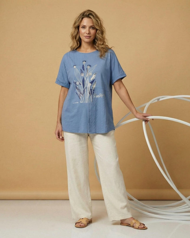 Снимка в цял ръст на синя лятна туника големи размери с овално деколте, красива апликация на цветя и вертикални панели от нежна дантела.