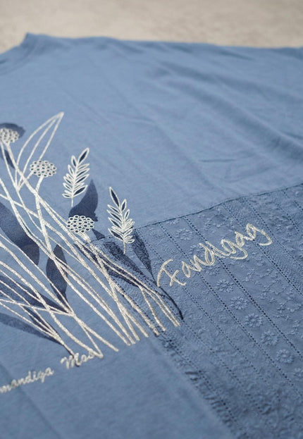 Детайл отблизо на синя лятна туника големи размери с флорална апликация, бродерия и красива дантела, разположена плосък кадър.