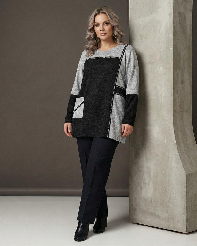 Стилна сива туника в големи размери с черен панел и страничен джоб, заснета върху модел в цял ръст до декоративна колона.