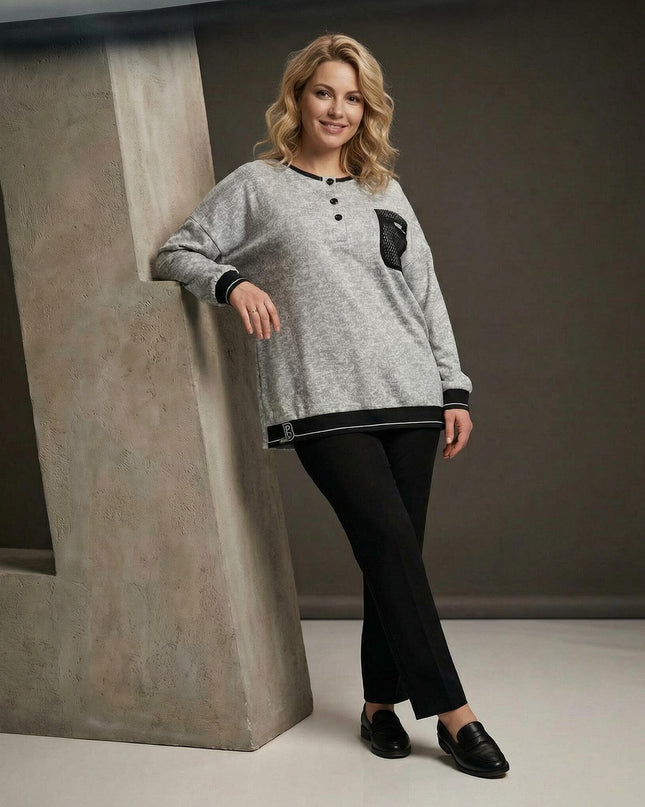 Светлосива туника меланж с декоративен джоб и мрежа, заснета в цял ръст върху модел. Виждат се черните кантове на подгъва и ръкавите, както и копчетата на деколтето.