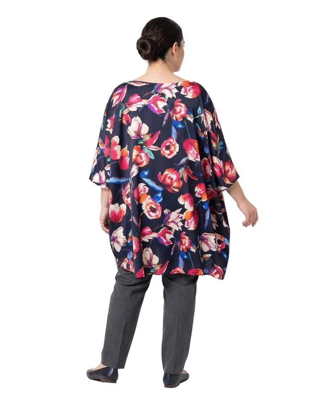 Изглед отзад на тъмносиня официална макси туника на цветя тип пончо. Моделът показва разкроената кройка и ефирния шифон с флорален принт.