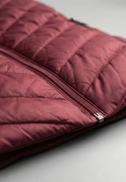 Детайл отблизо на зимно макси яке в бордо, показващ вълнообразното капитониране на материята и качествения преден цип.