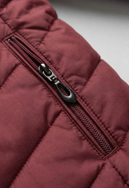 Детайл отблизо на джоб с цип върху зимно макси яке в бордо, показващ капитонираната полиестерна материя и качествената изработка.